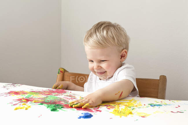 Menino brincando com pinturas de dedo — Fotografia de Stock