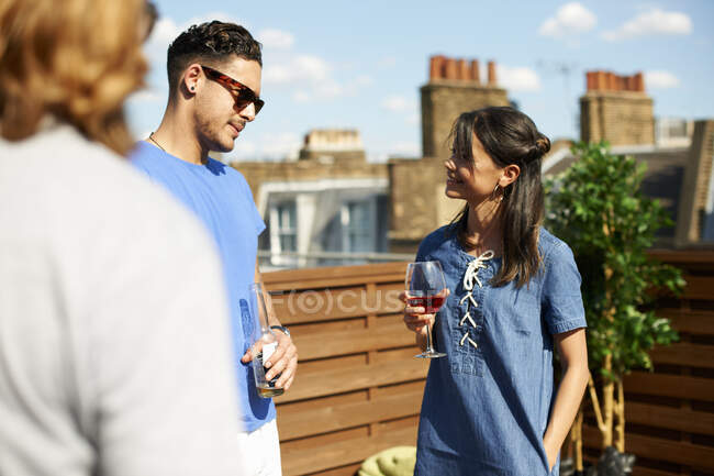 Amigos masculinos e femininos conversando e bebendo na festa no telhado — Fotografia de Stock