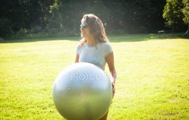 Mid adult woman holding up exercise ball in field — Stock Photo