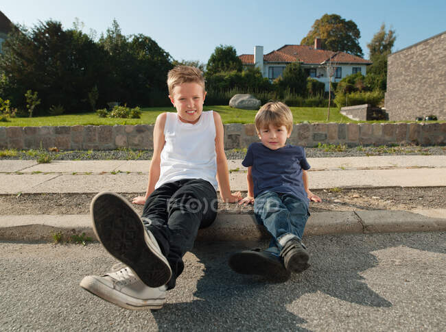 Brothers sitting together on sidewalk — Stock Photo