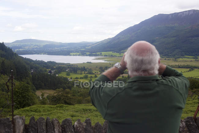 Rear view of man birdwatching at viewpoint between Braithwaite Village and Whinlatter, Cumbria, UK — Stock Photo