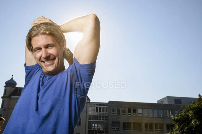 Homme adulte mi-étirement pendant l'entraînement sur le toit de la ville — Photo de stock