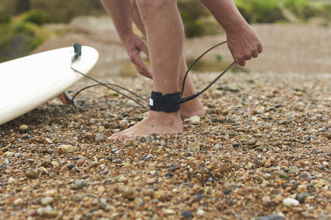 Uomo lega il guinzaglio della tavola da surf alla caviglia — Foto stock
