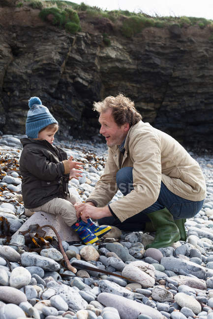 Father and son playing on rocky beach — Stock Photo