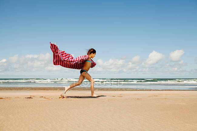 Fille courir avec couverture à la plage — Photo de stock