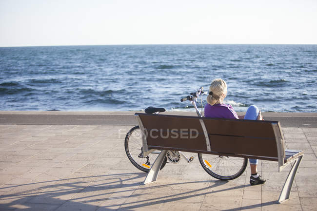 Donna anziana godendo vista sull'oceano sulla panchina — Foto stock