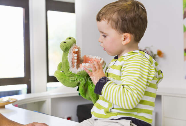 Boy playing with toy crocodile in dentists — Stock Photo