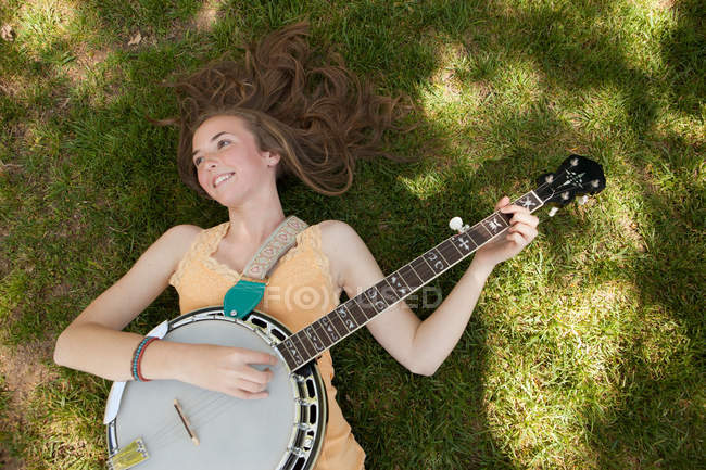 Дівчина-підліток грає банджо на траві, вид зверху — стокове фото