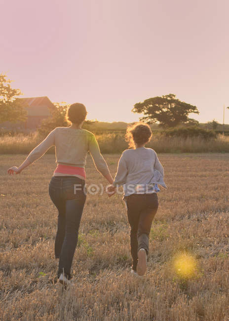 Madre e hija corriendo en el campo - foto de stock