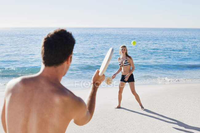 Couple playing tennis on beach — Stock Photo