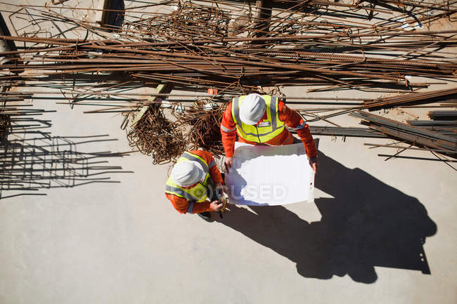 Рабочие, читающие чертежи на месте — стоковое фото