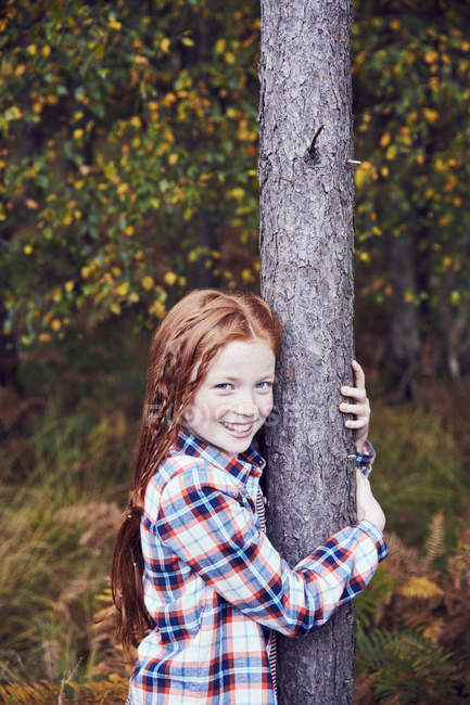 Retrato de menina, árvore abraçando, sorrindo — Fotografia de Stock