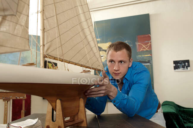 Junger Mann studiert Modell eines Schiffes — Stockfoto