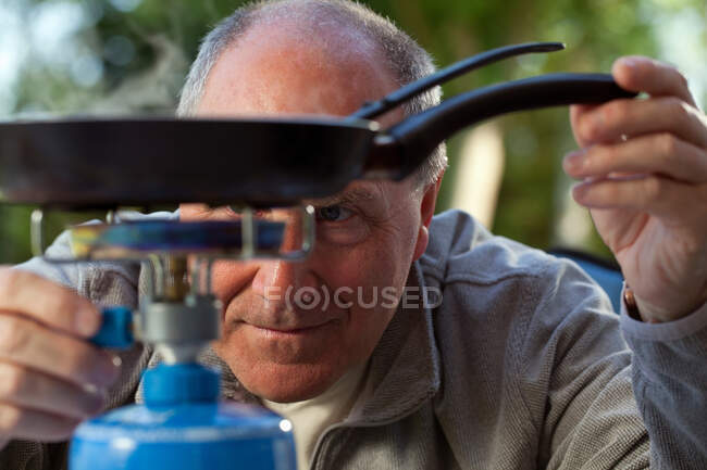 Senior man cooking on camping stove — Stock Photo