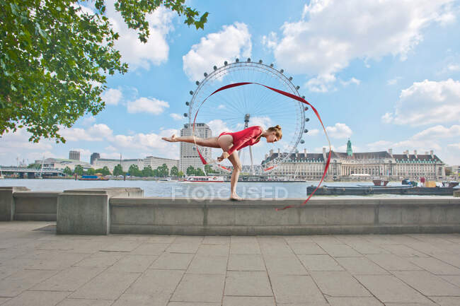 Gymnast twirling ribbon on city street — Stock Photo