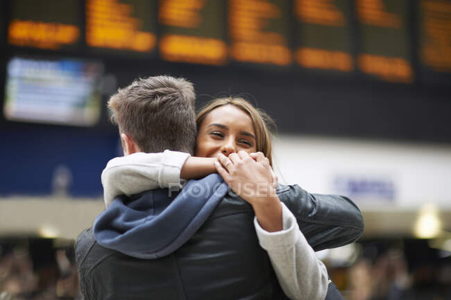 Pareja heterosexual abrazándose en la estación de tren, vista trasera - foto de stock
