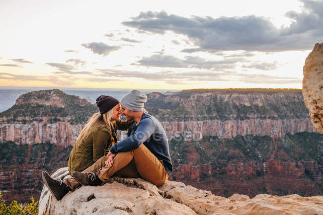 Пара сидящих и обнюхивающих на краю Гранд Каньона, Аризона, США — стоковое фото