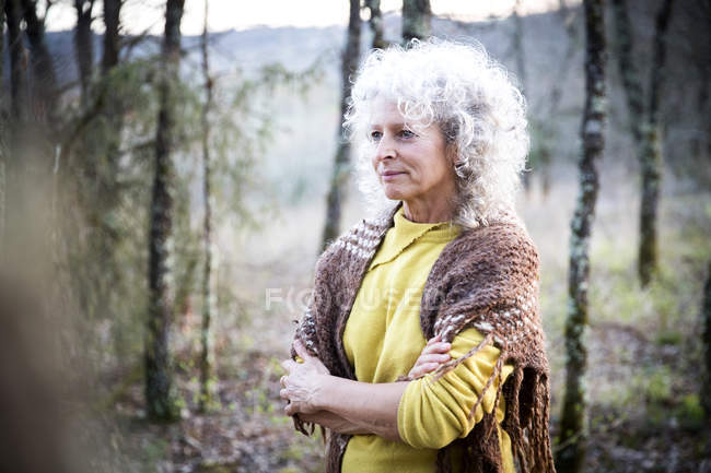 Donna matura in piedi nel bosco con le braccia incrociate — Foto stock