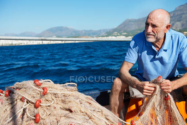 Pescatore che tiene reti con il mare sullo sfondo — Foto stock