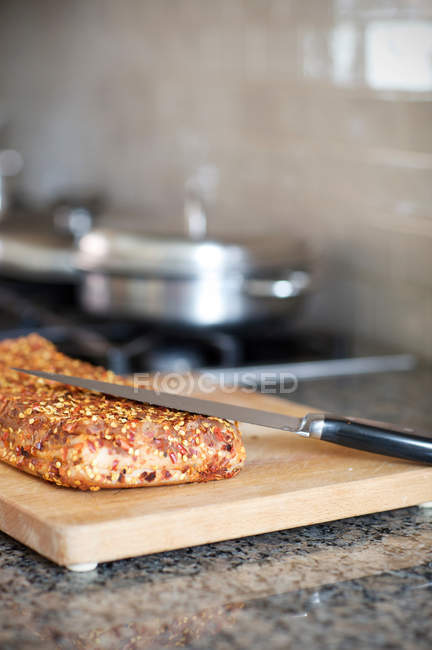 Pancetta viande avec couteau sur planche à découper en bois — Photo de stock