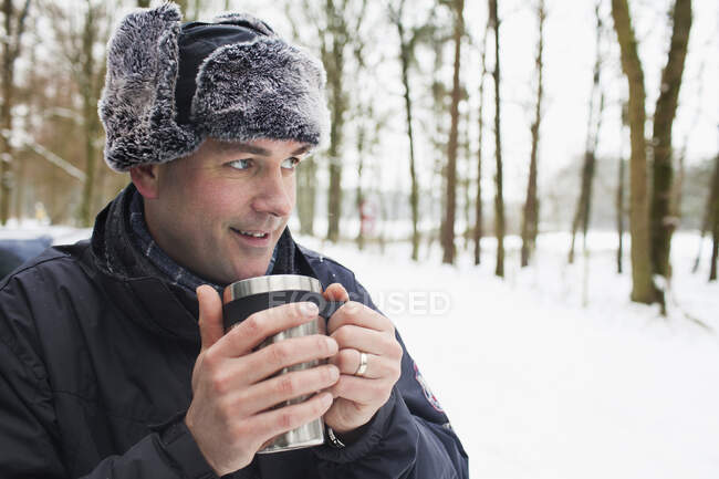 Mature man having hot drink outside in winter — Stock Photo