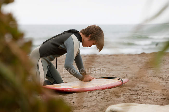 Rapaz encerando prancha de surf na praia — Fotografia de Stock