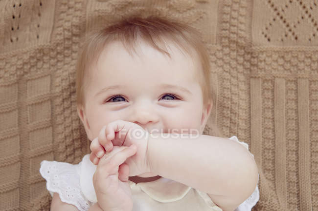 Portrait en gros plan d'une petite fille souriante allongée sur une couverture — Photo de stock