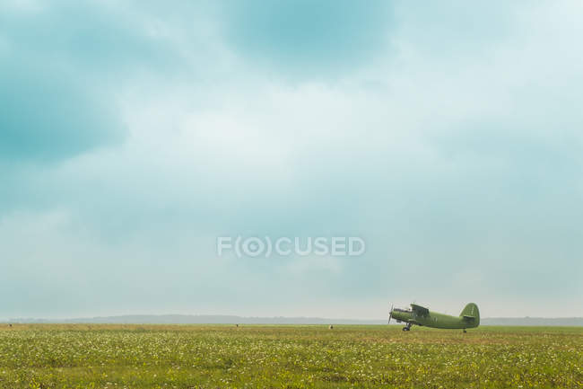 Aereo d'epoca sul campo con cielo nuvoloso — Foto stock