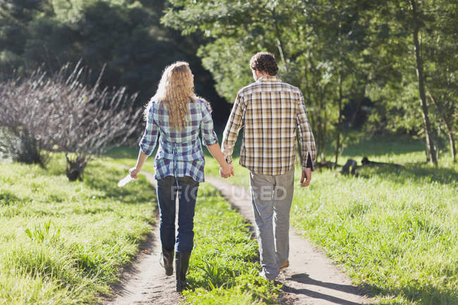 Пара идущих рука об руку по грунтовой дорожке — стоковое фото