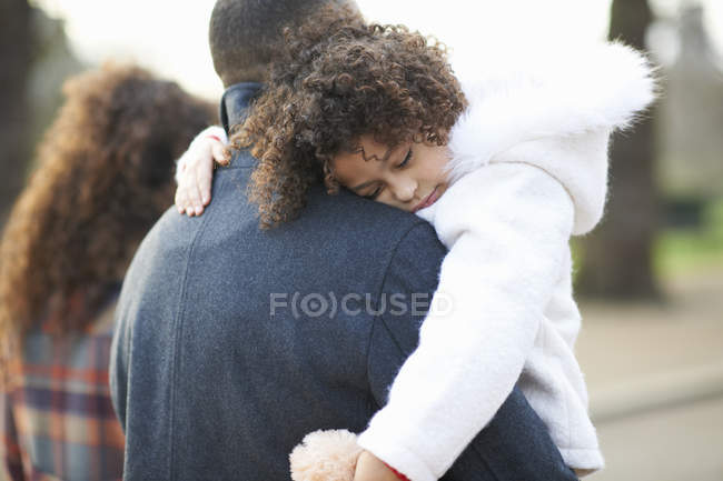 Vista trasera del padre llevando a la hija dormida - foto de stock