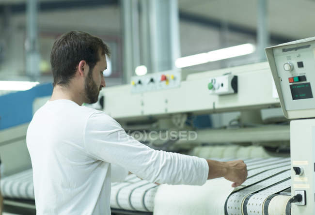 Hombre en lavandería usando máquina de planchar - foto de stock