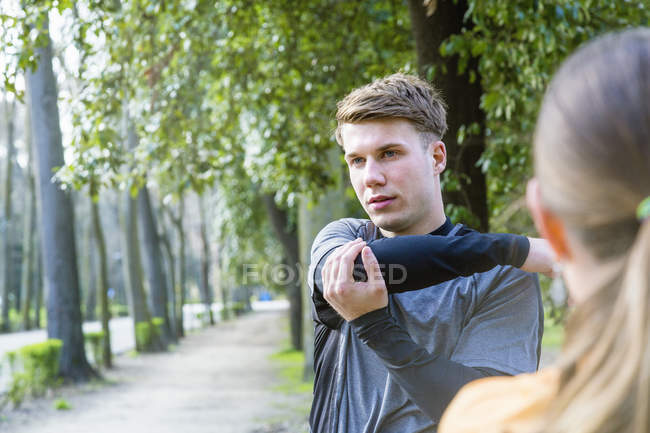 Young man exercising outdoors, stretching — Stock Photo