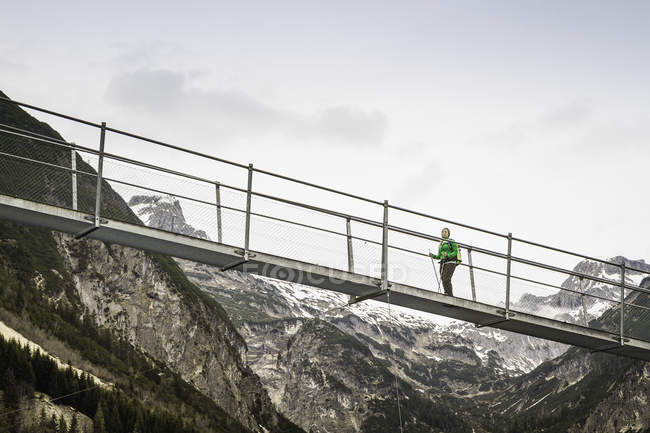 Low angle view of woman hiking on foot bridge, Holzgau, Tirol, Austria — стоковое фото
