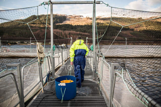 Worker at salmon farm in rural lake — Stock Photo