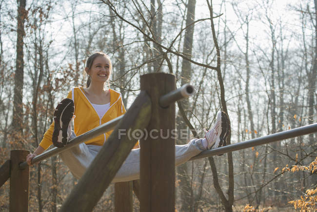 Young woman balancing on parallel bars on forest assault course — Stock Photo