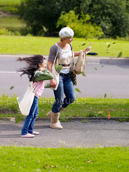 Madre e hija caminando en el viento - foto de stock