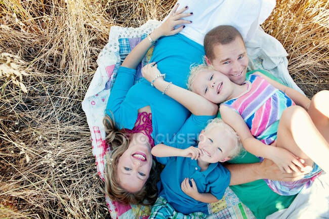 Семья с двумя детьми, лежащими в поле — стоковое фото