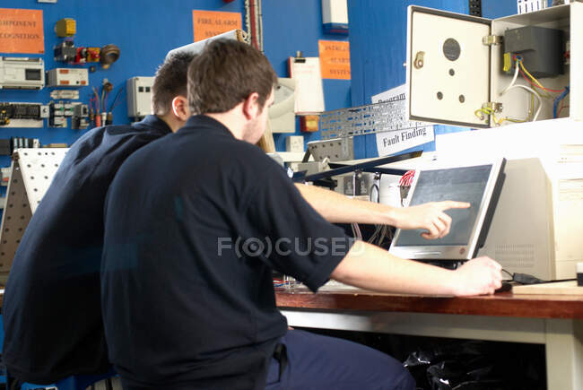 Ingenieros eléctricos trabajando en computadoras - foto de stock