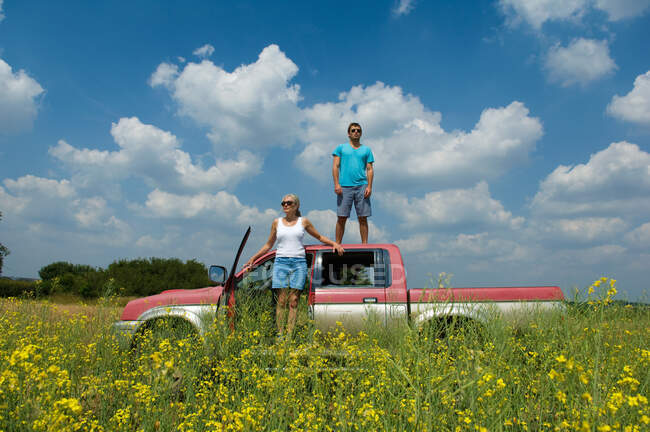 Mother and son with pickup truck in field, son standing on top of truck — Stock Photo