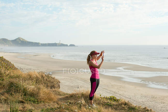 Активная молодая женщина фотографирует на пляже — стоковое фото