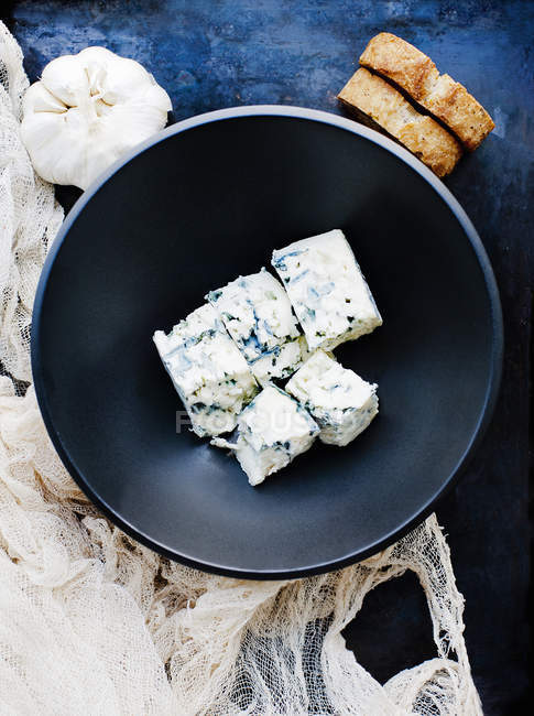 Garlic bulb and bowl of cubed blue cheese — Stock Photo