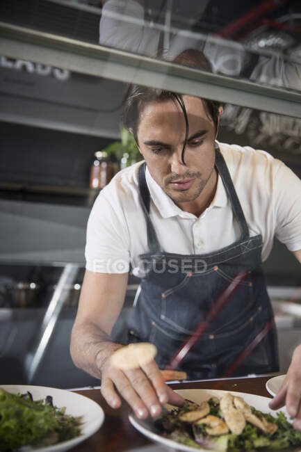 Restaurador preparando salada atrás do balcão de serviço — Fotografia de Stock