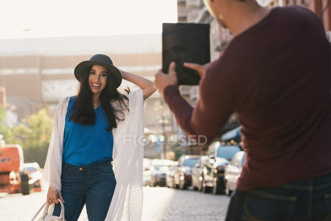 Homem adulto médio fotografar namorada usando tablet digital na rua da cidade — Fotografia de Stock