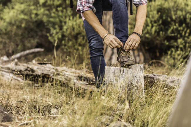 Waist down view of male hiker tying hiking boot laces, Deer Park, Cape Town, South Africa — Stock Photo