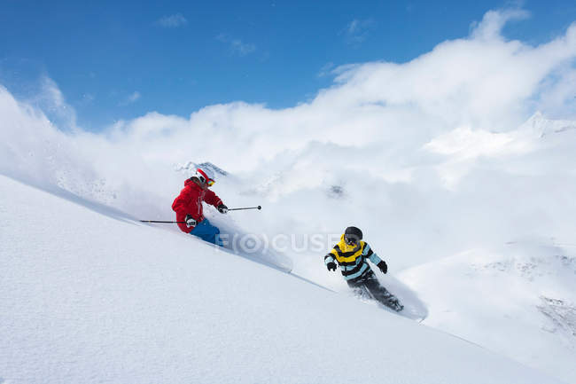 Skier and snowboarder on snowy slope — Stock Photo