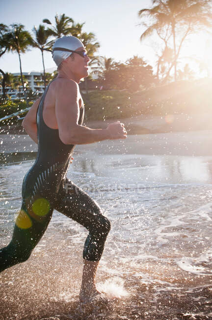 Nadador correndo em ondas na praia — Fotografia de Stock
