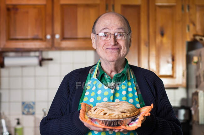 Senior man holding freshly baked pie, portrait — Stock Photo