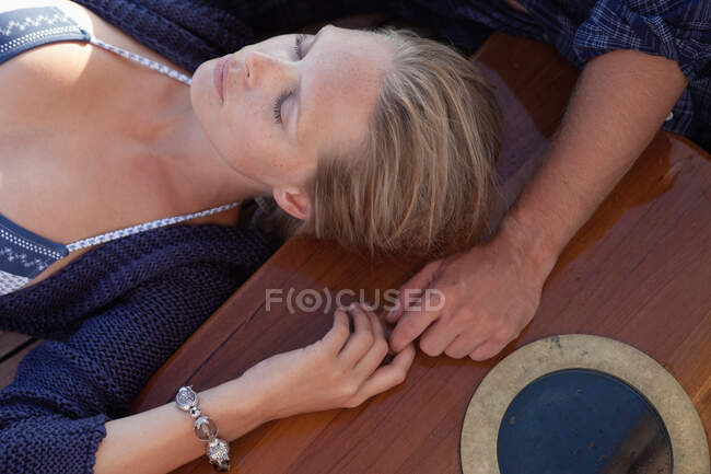 Couple lying on deck holding hands — Stock Photo