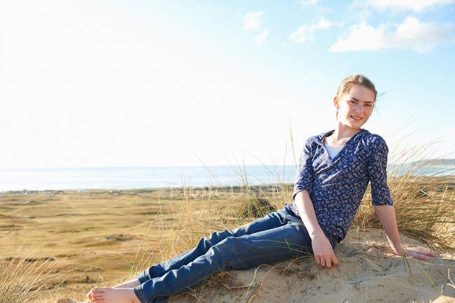 Chica adolescente sentada en la playa - foto de stock