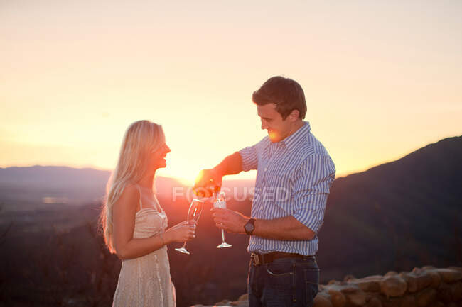 Giovane coppia avendo champagne all'aperto al tramonto — Foto stock
